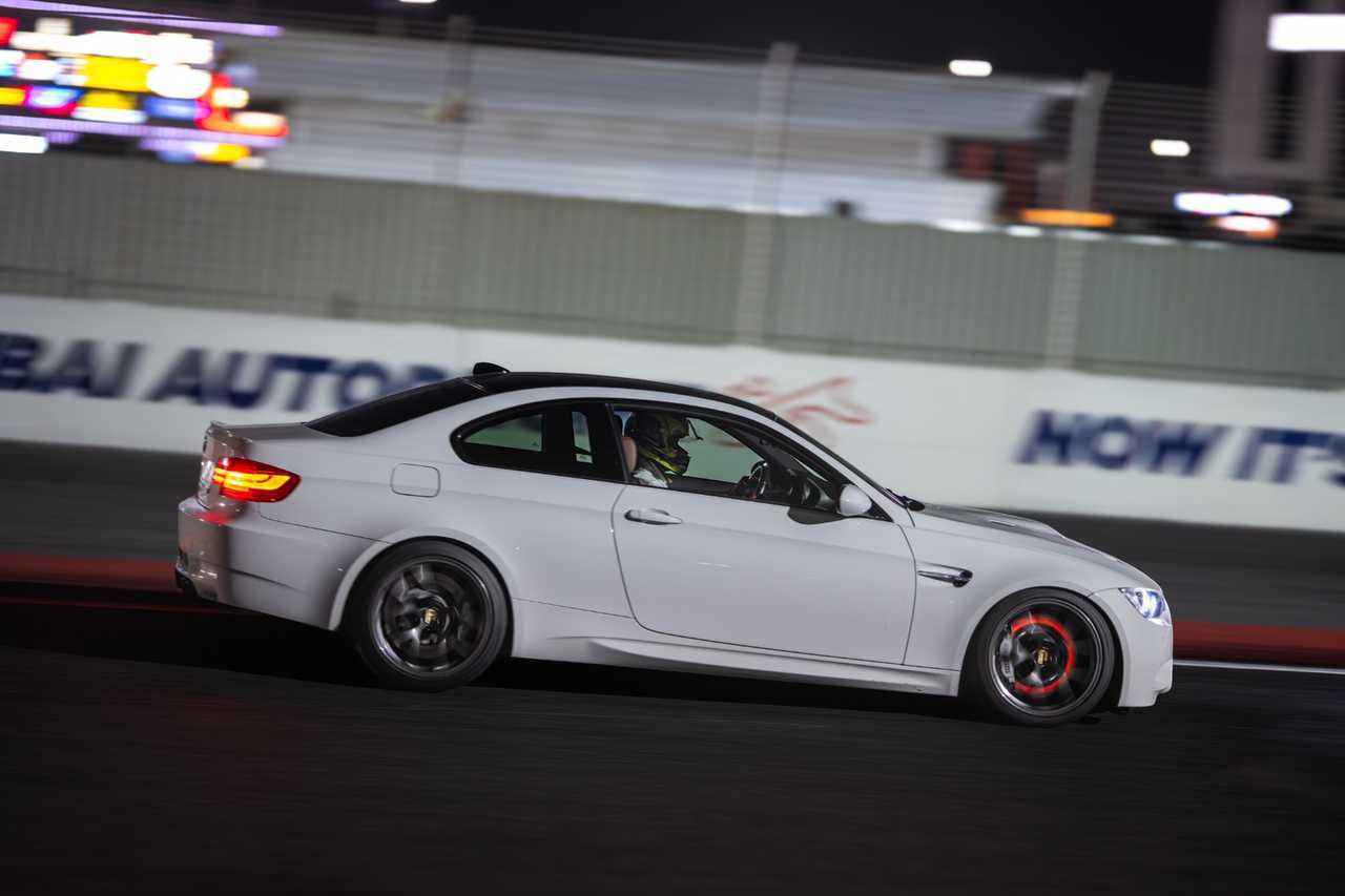 A white, modified BMW M3 E92 coupe on a night track | ATOMIC-SHOP