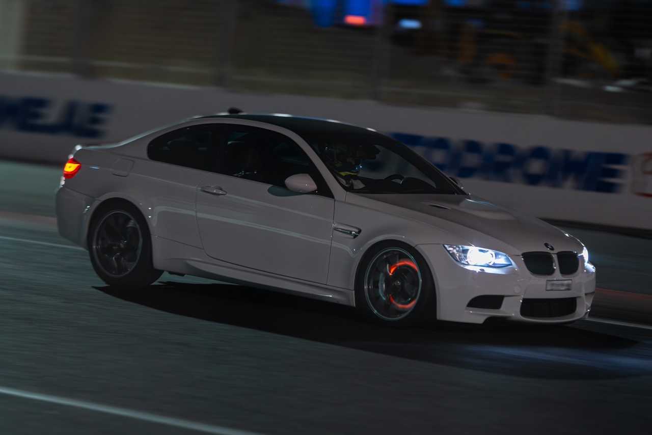 A white, modified BMW M3 E92 coupe on a night track | ATOMIC-SHOP